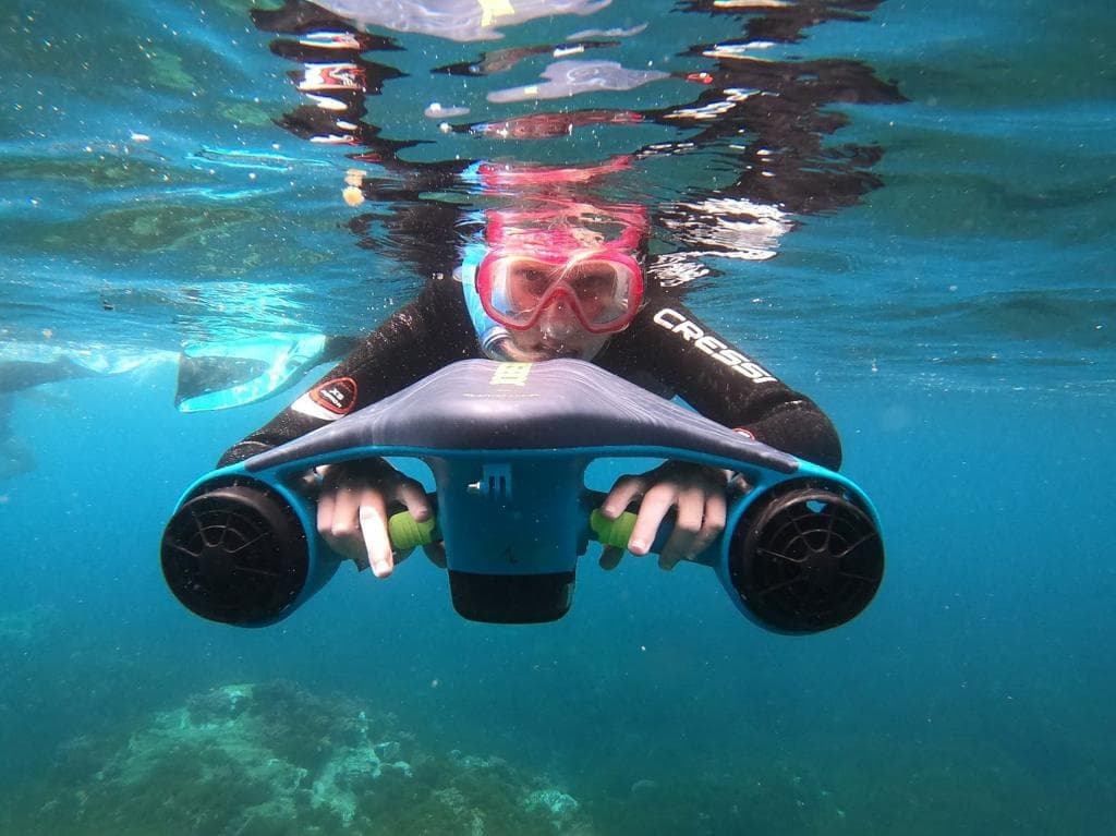 Explorador utilizando un scooter subacuático para hacer snorkel en las aguas cristalinas de Maro, Nerja.