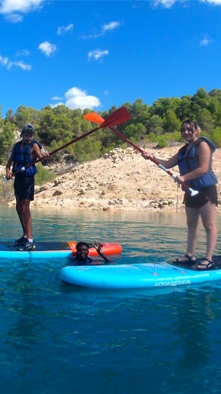 Grupo de personas con un guía practicando paddle surf en las aguas cristalinas del río Cabriel.