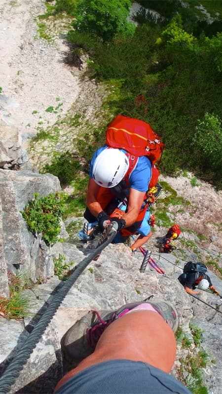 Deportista progresando por los peldaños de una vía ferrata en Venta del Moro con las Hoces del Cabriel de fondo.