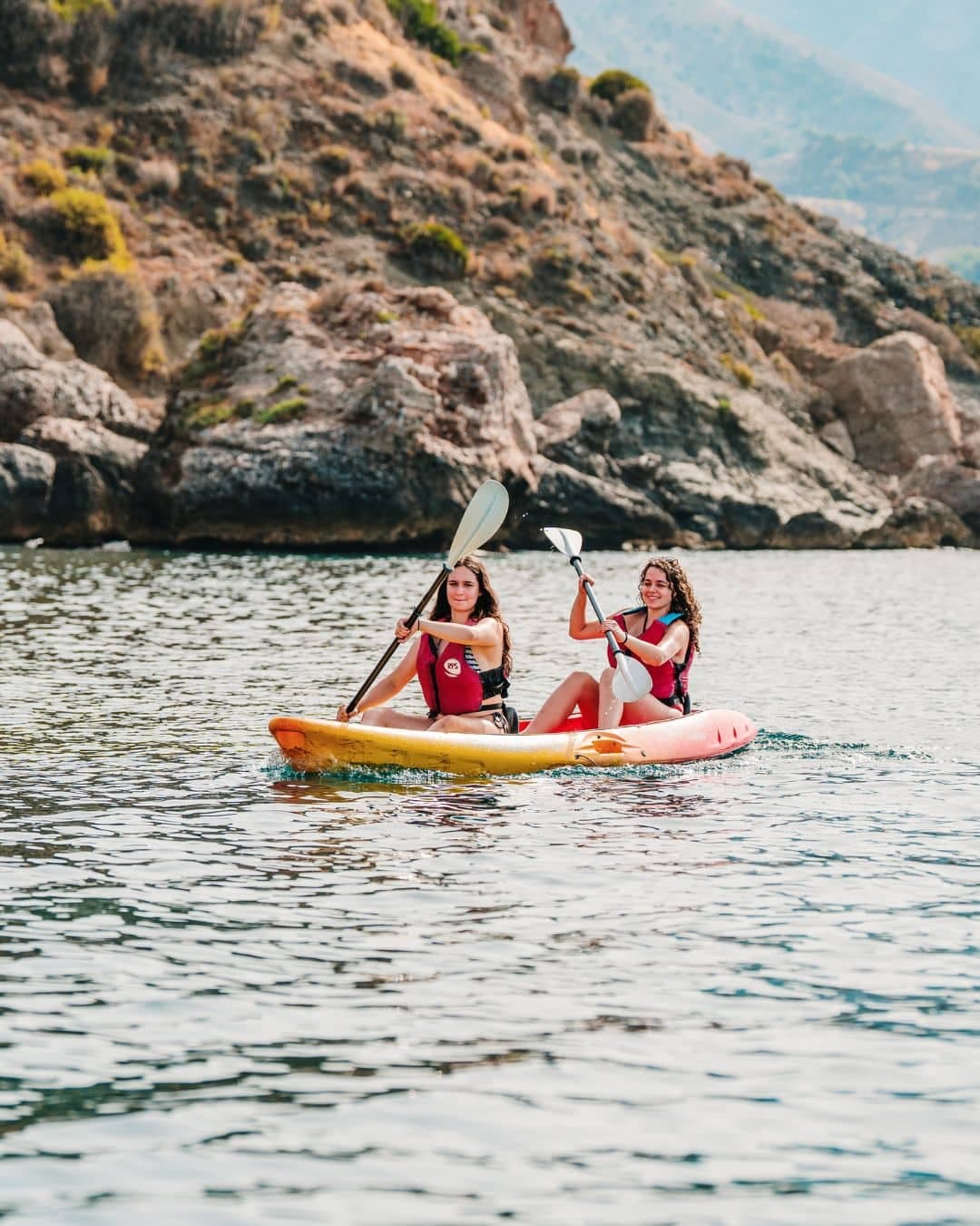 Grupo de personas en kayak navegando cerca de la Cascada de Maro en los acantilados de Nerja.