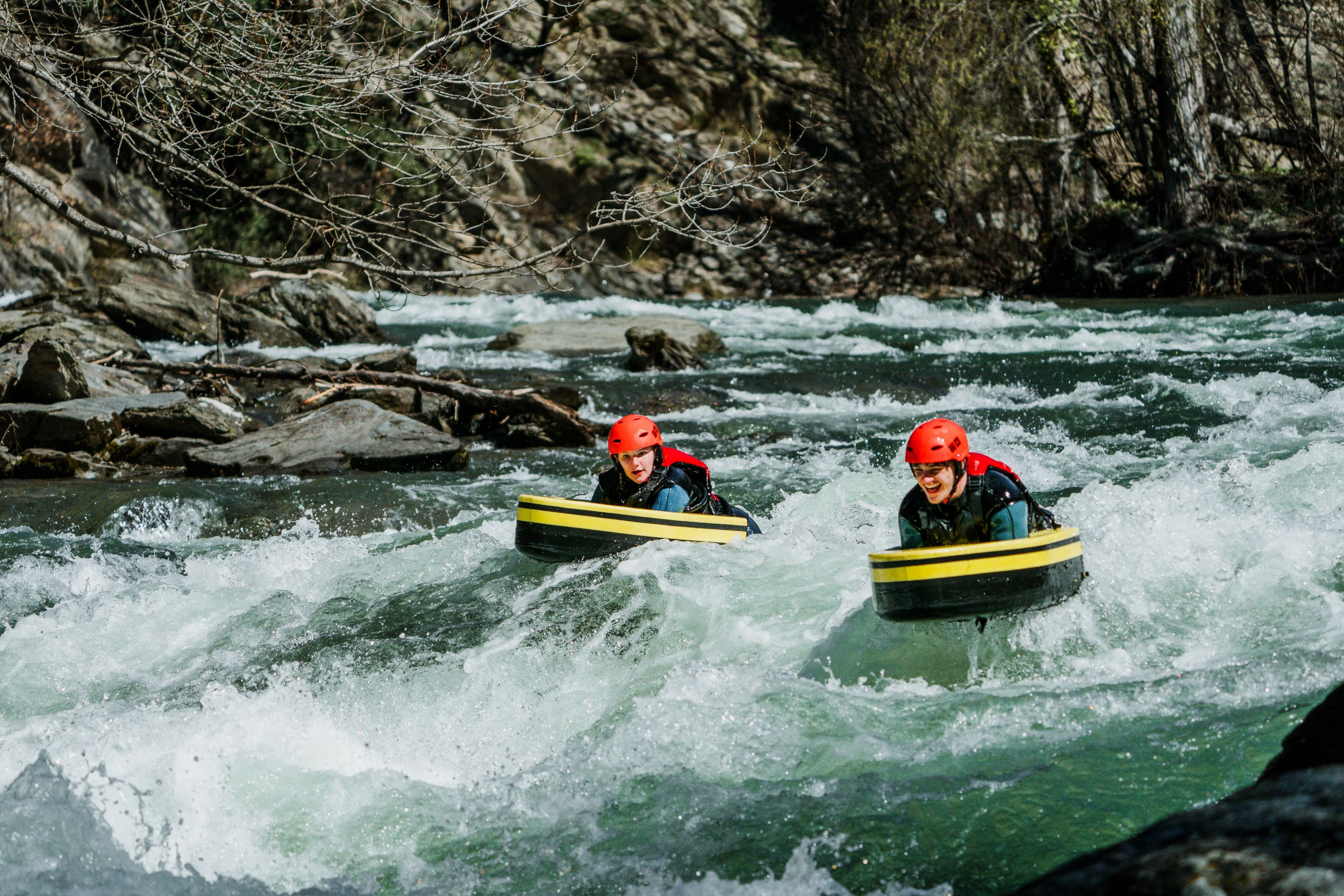 Persona equipada con casco y traje reforzado navegando por un rápido del río Noguera Pallaresa sobre una tabla de hidrospeed.