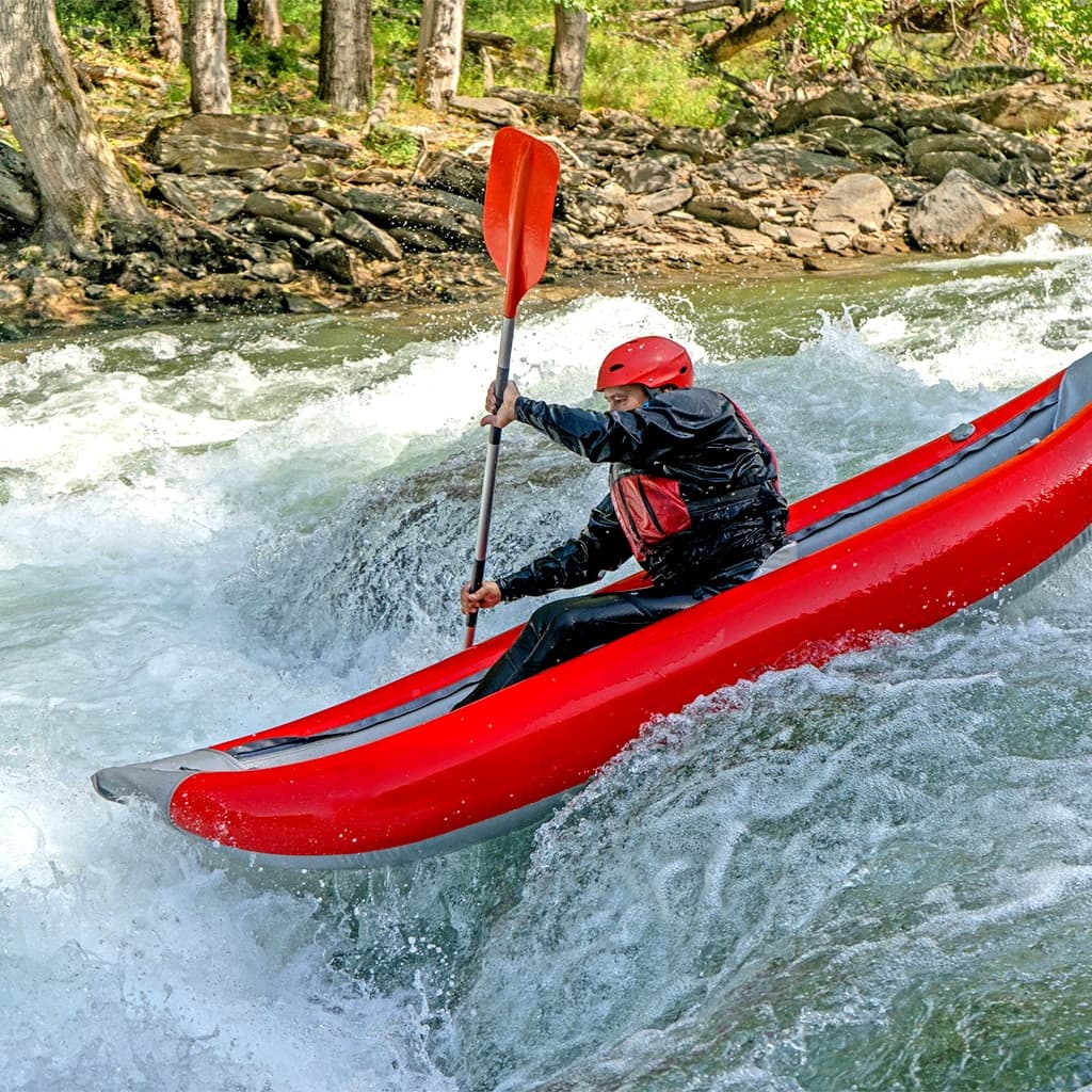 Kayakistas navegando por un tramo de aguas bravas del río Noguera Pallaresa en un open kayak autovaciable.