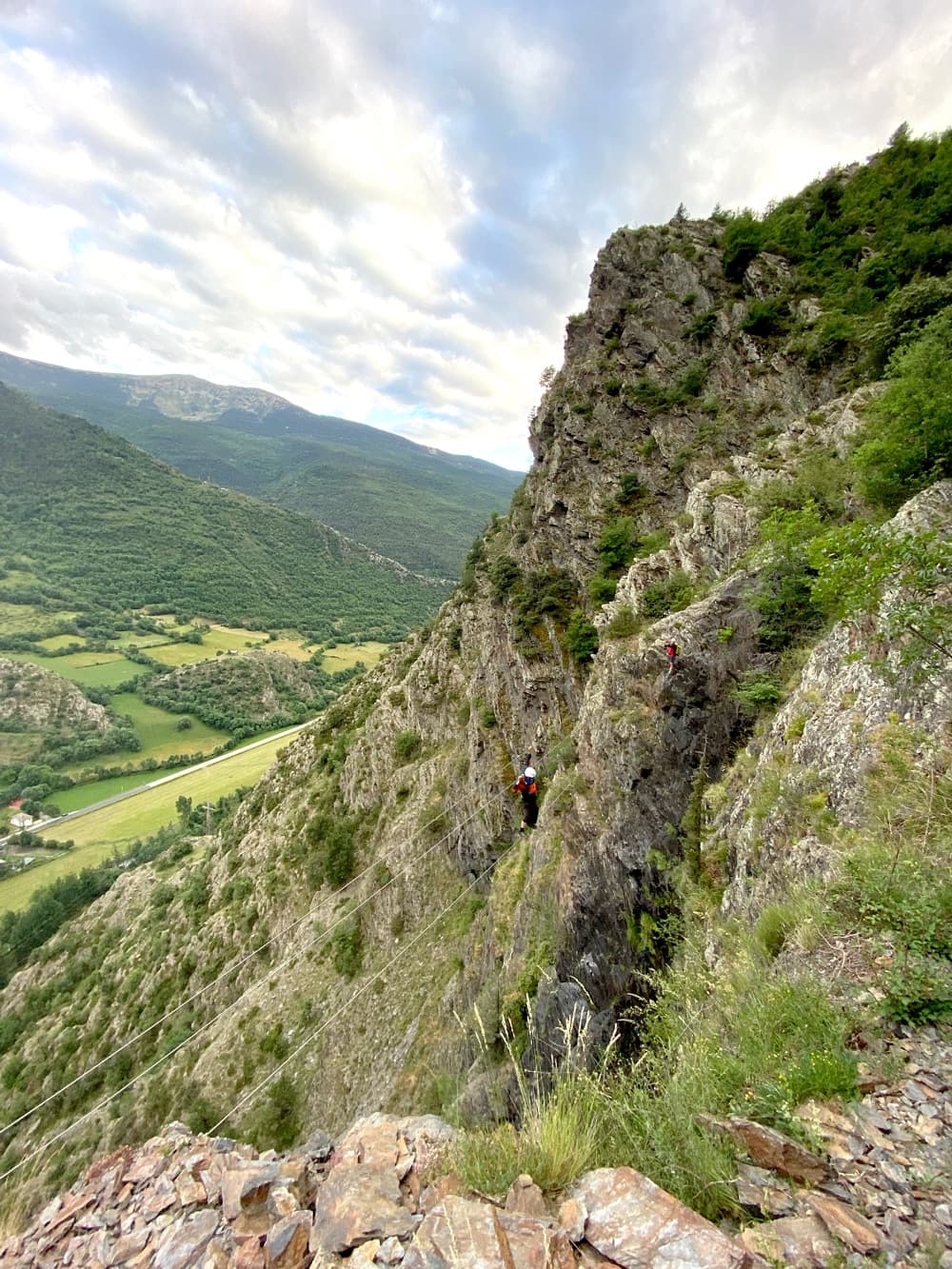 Persona equipada con arnés y casco progresando por los peldaños metálicos de la Vía Ferrata Salt del Botanal en Alins.