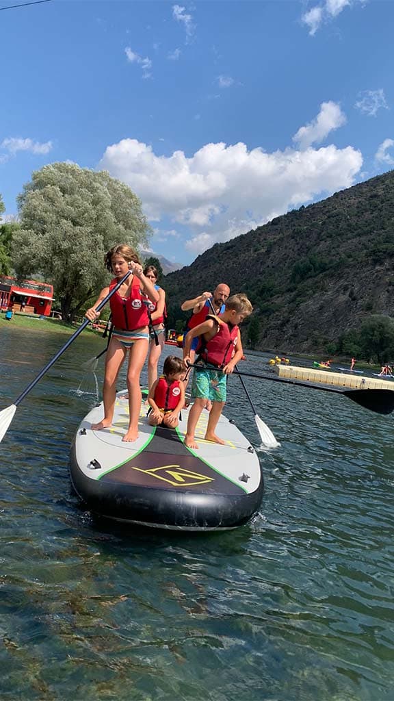Grupo de personas coordinándose para remar sobre una tabla gigante de Big SUP en el Lago de La Torrassa.