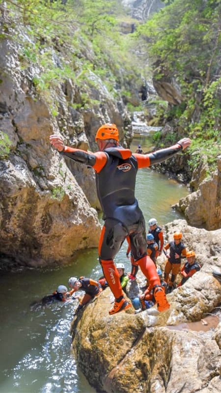 Grupo de personas con neopreno y casco preparándose para un salto en el Barranco del Río Blanco, Pirineos.